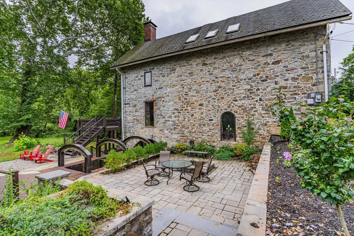 Stone exterior with patio seating, wooden bridge, and American flag