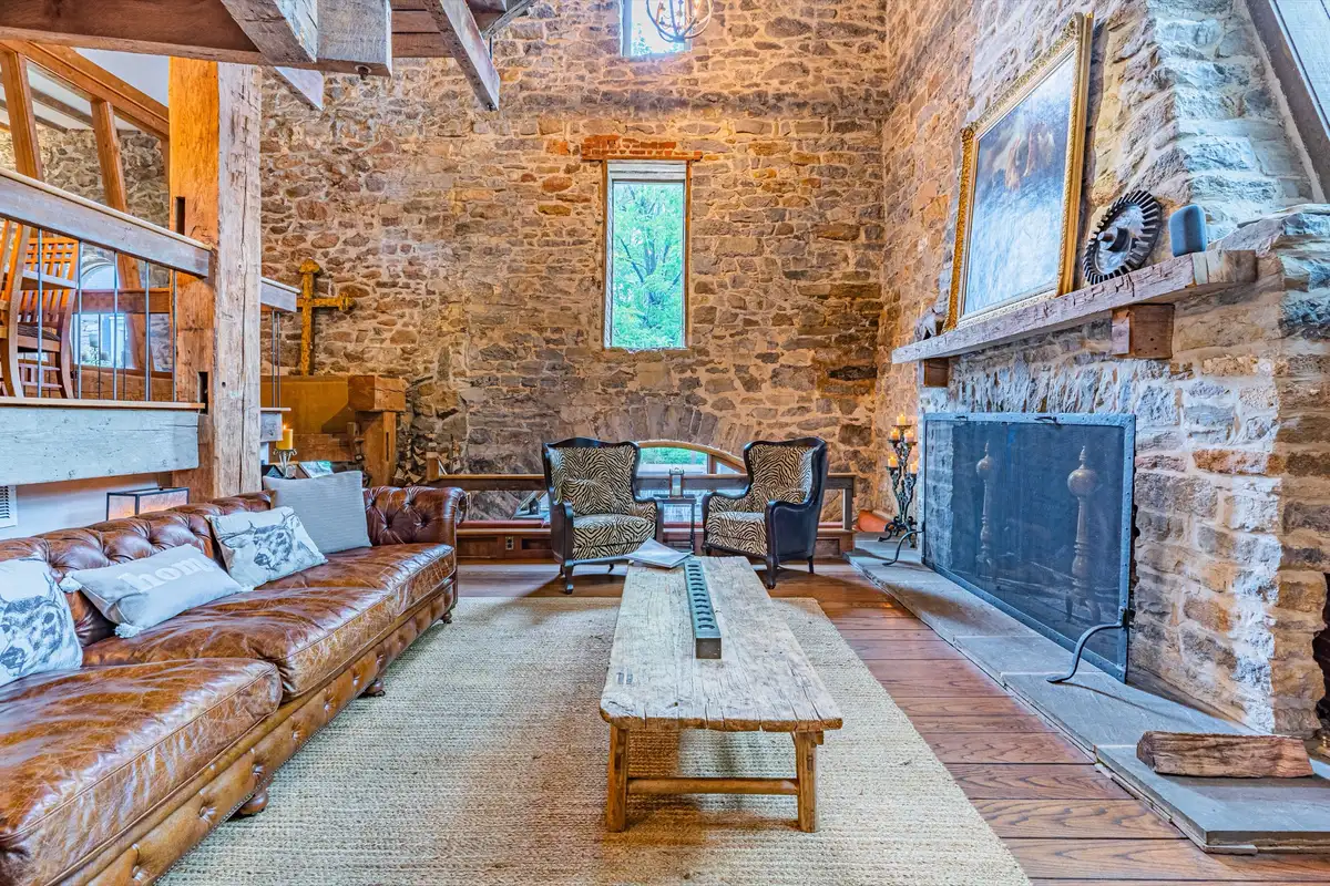 Living room with leather sofa, stone fireplace, and soaring ceilings