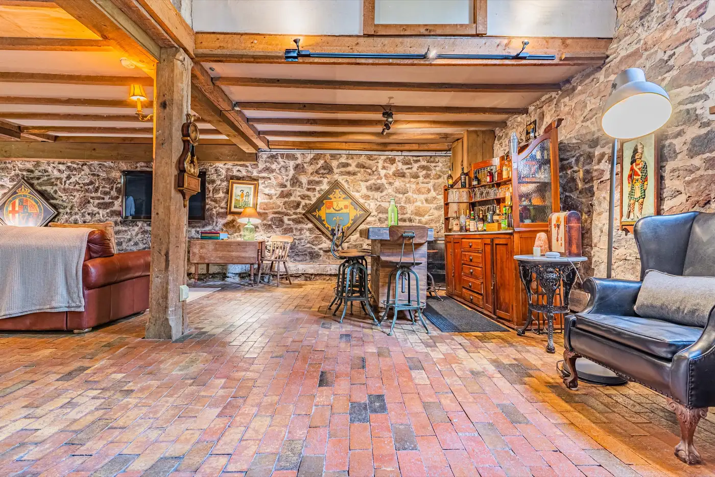 Basement lounge with brick floor, bar area, and leather chairs