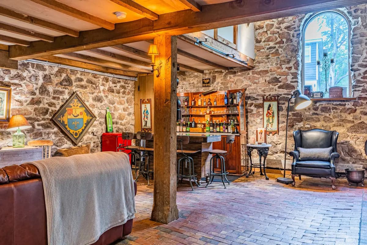 Stone-walled pub area with brick floor, leather armchair, and warm lighting