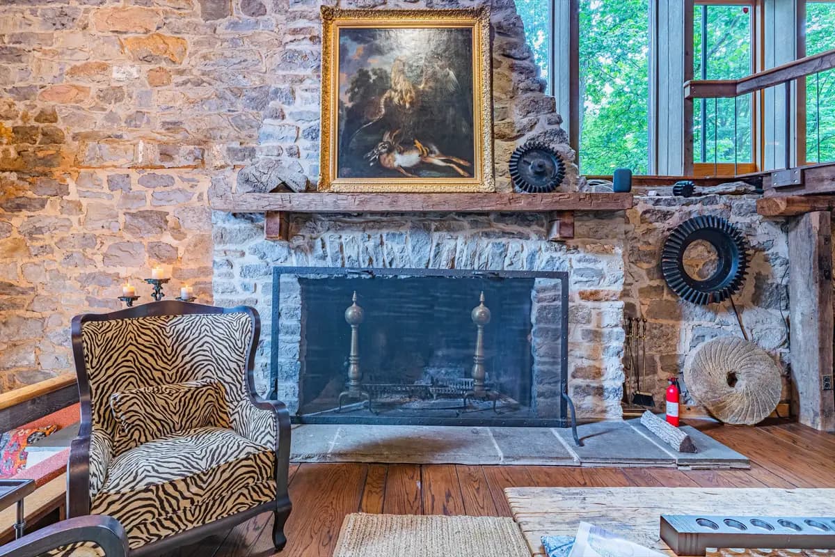 Grand living room with stone fireplace, leather sofa, and original millstone decor