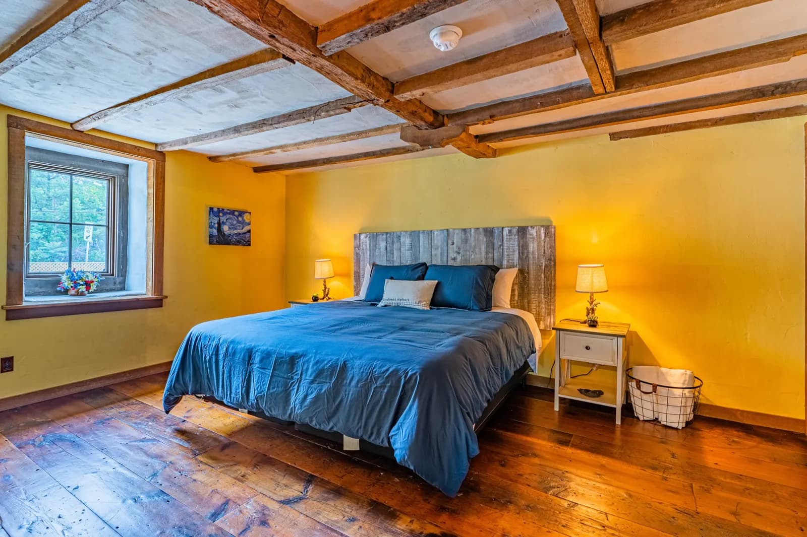 Yellow bedroom with blue bedding and exposed beam ceiling