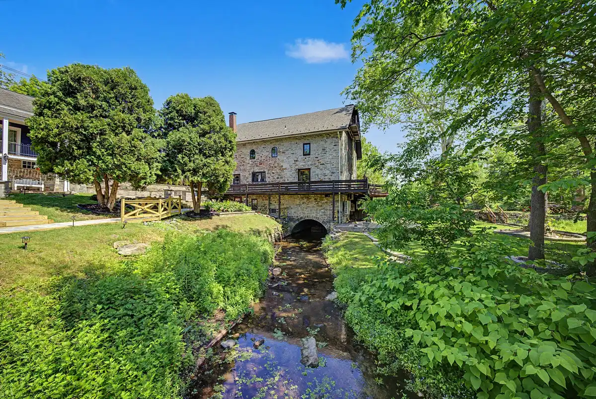 The millstream running away from the stone mill through dense summer greenery