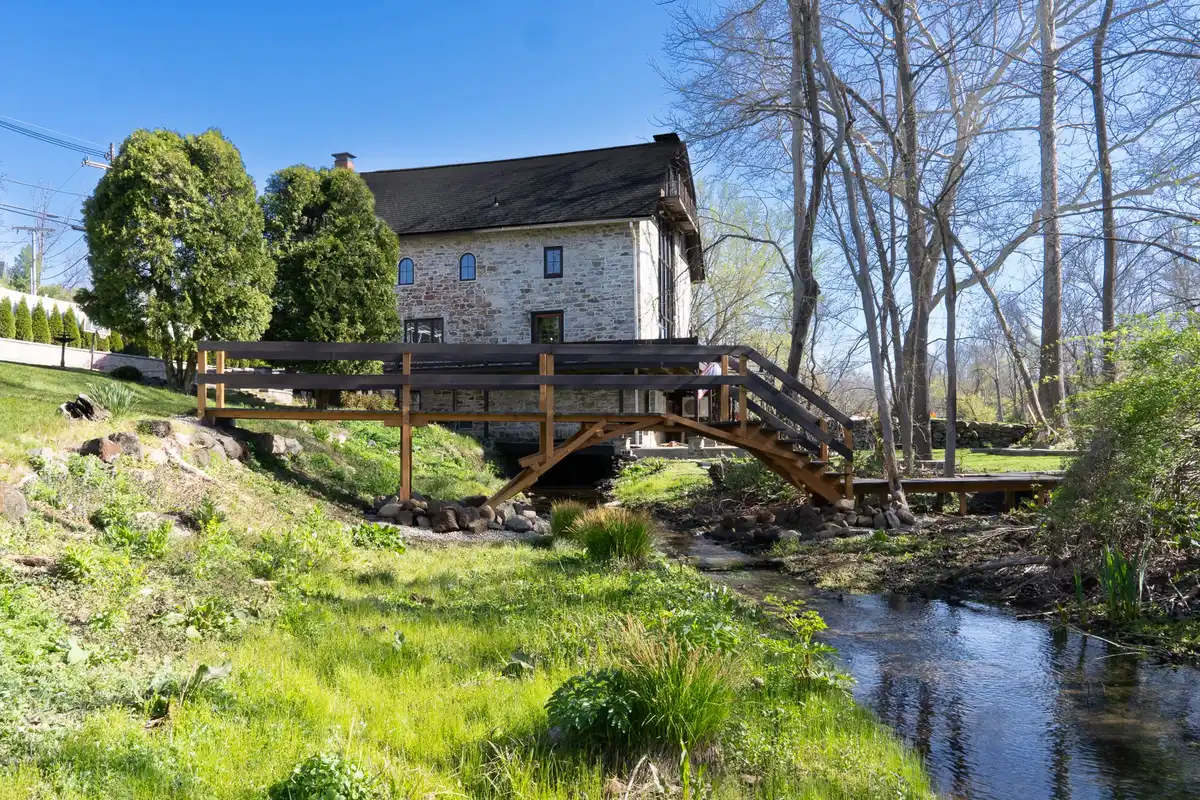 The stone mill in early spring with the footbridge and stream in the foreground