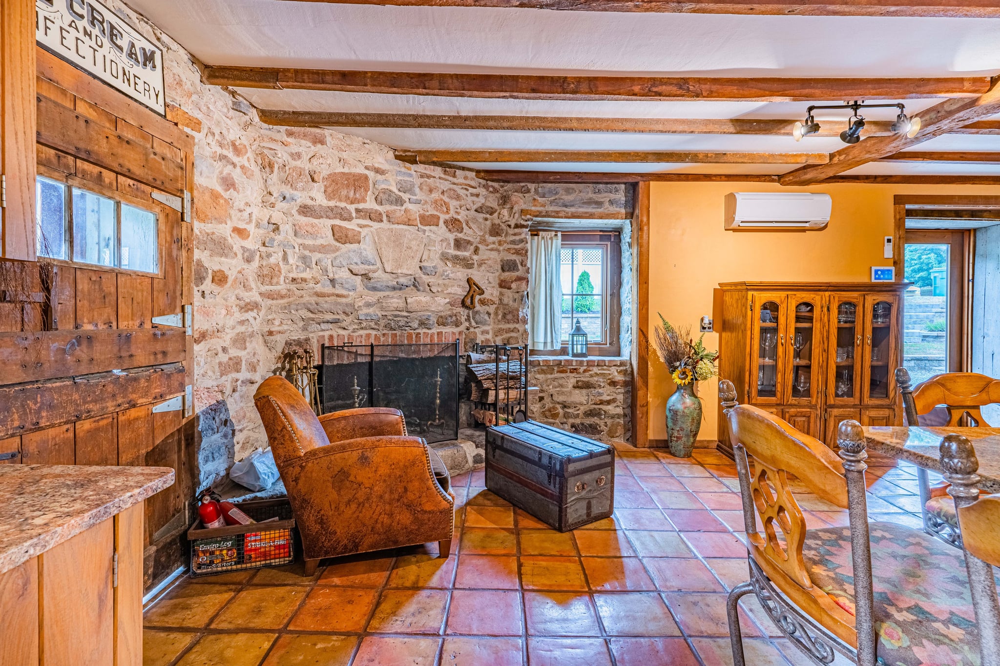 Cozy sitting room with stone fireplace, leather armchair, and exposed beams
