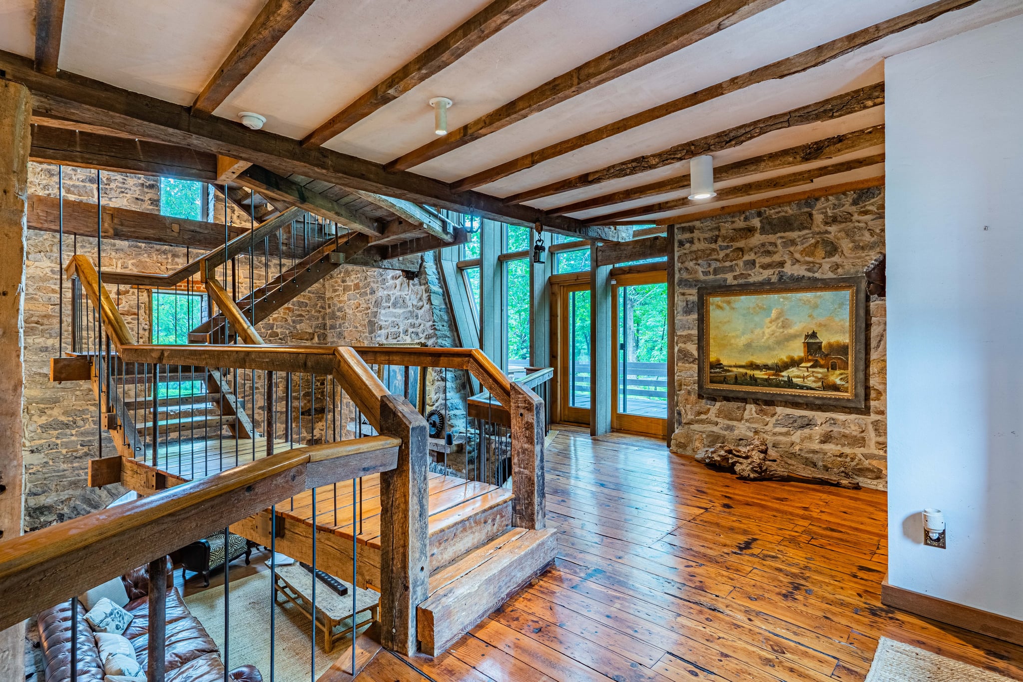 Landing with original timber staircase, stone walls, and oil painting