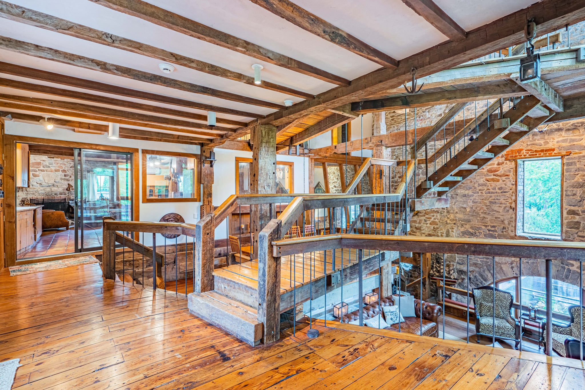 Bedroom with quilted bedding, stone wall, and wooden beams