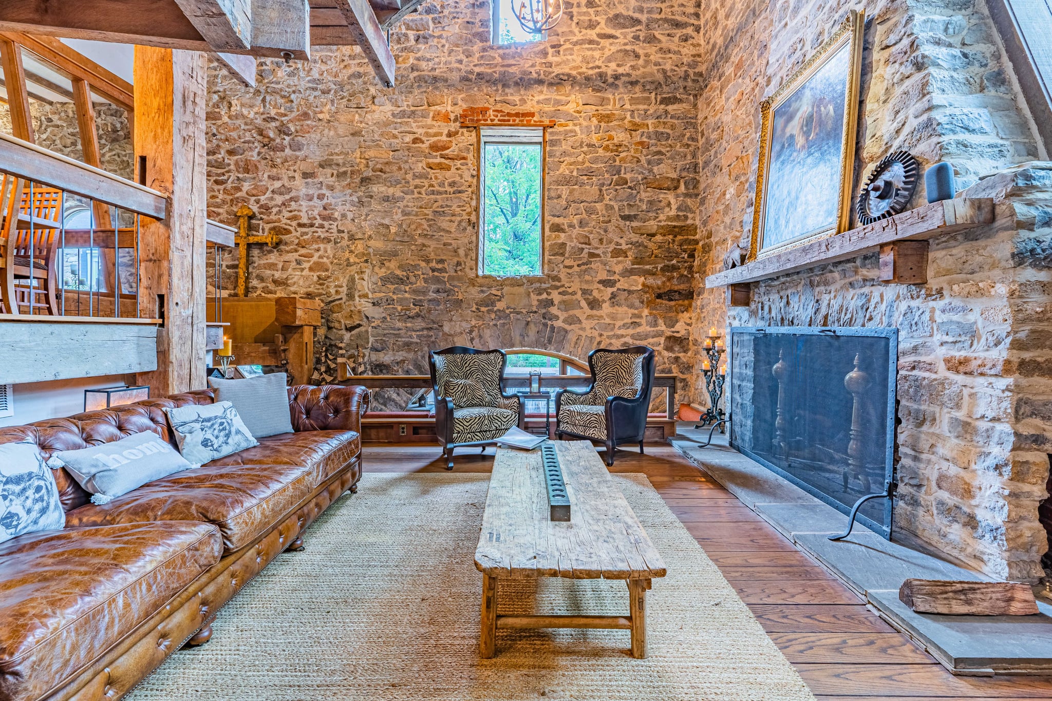 Living room with leather sofa, stone fireplace, and soaring ceilings