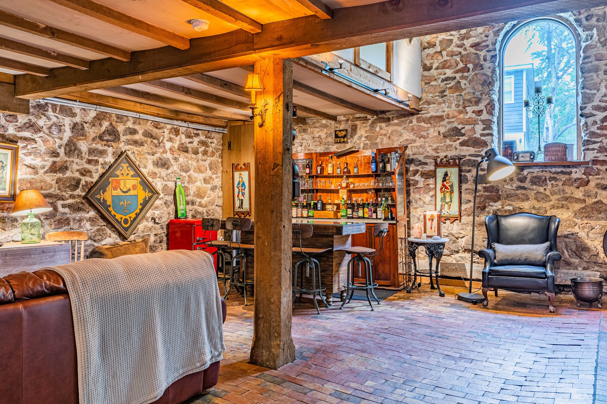 Stone-walled pub area with brick floor, leather armchair, and warm lighting