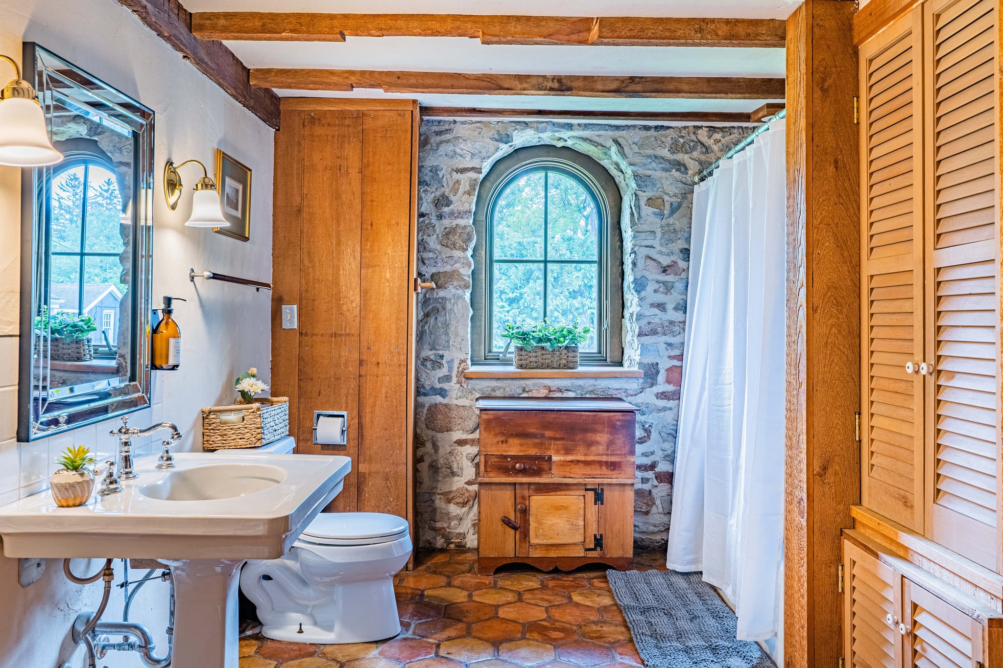 Rustic bathroom with stone wall and arched window