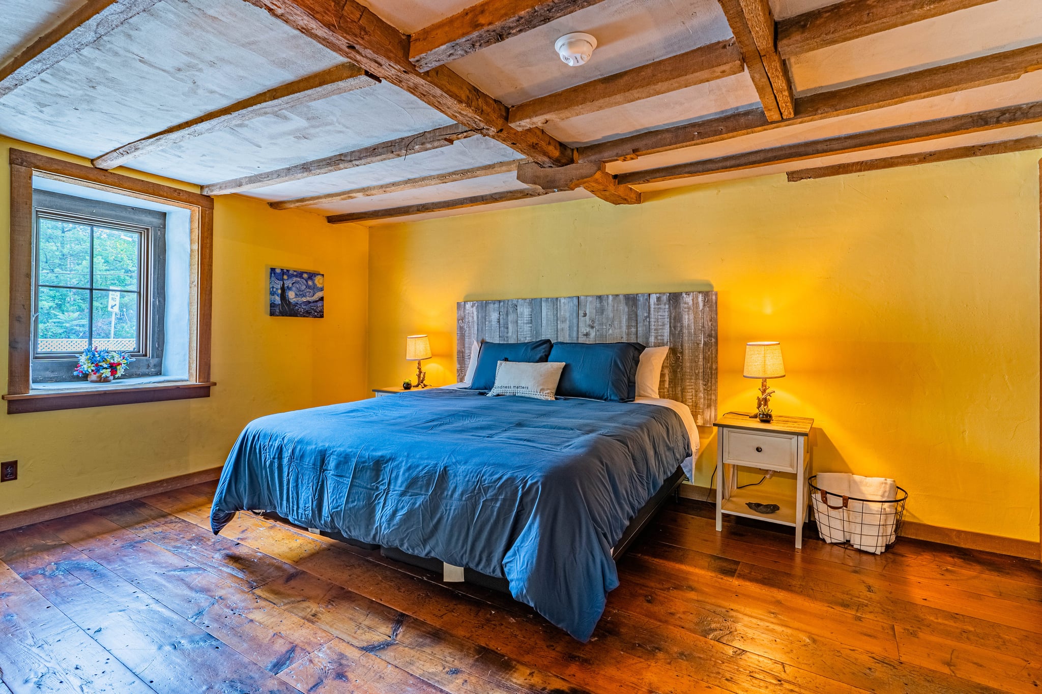 Yellow bedroom with blue bedding and exposed beam ceiling