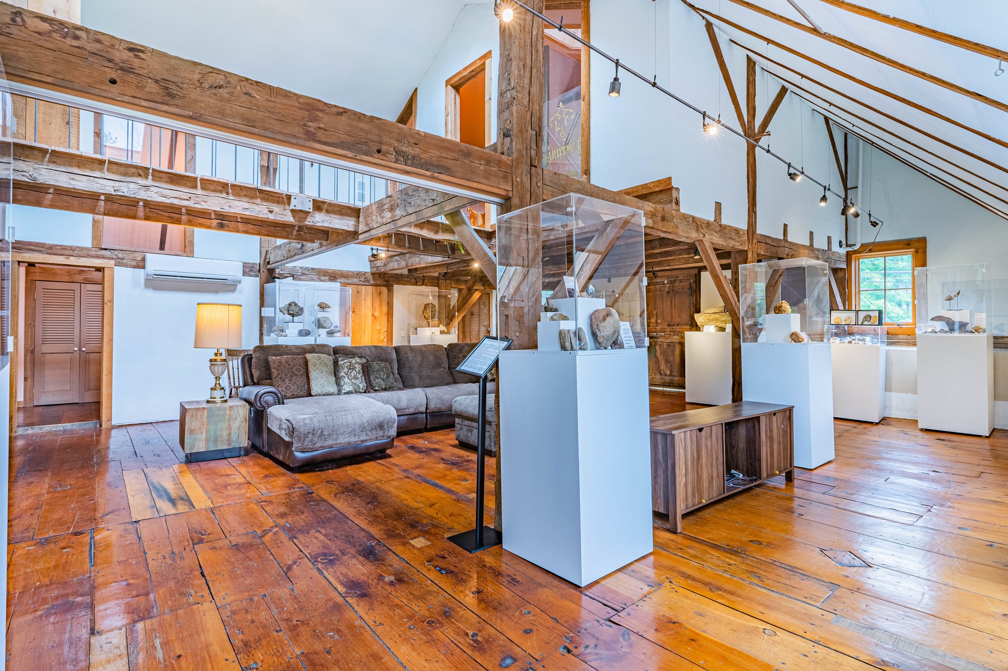 Furnished sitting area with stone wall, vintage poster art, and hardwood floors