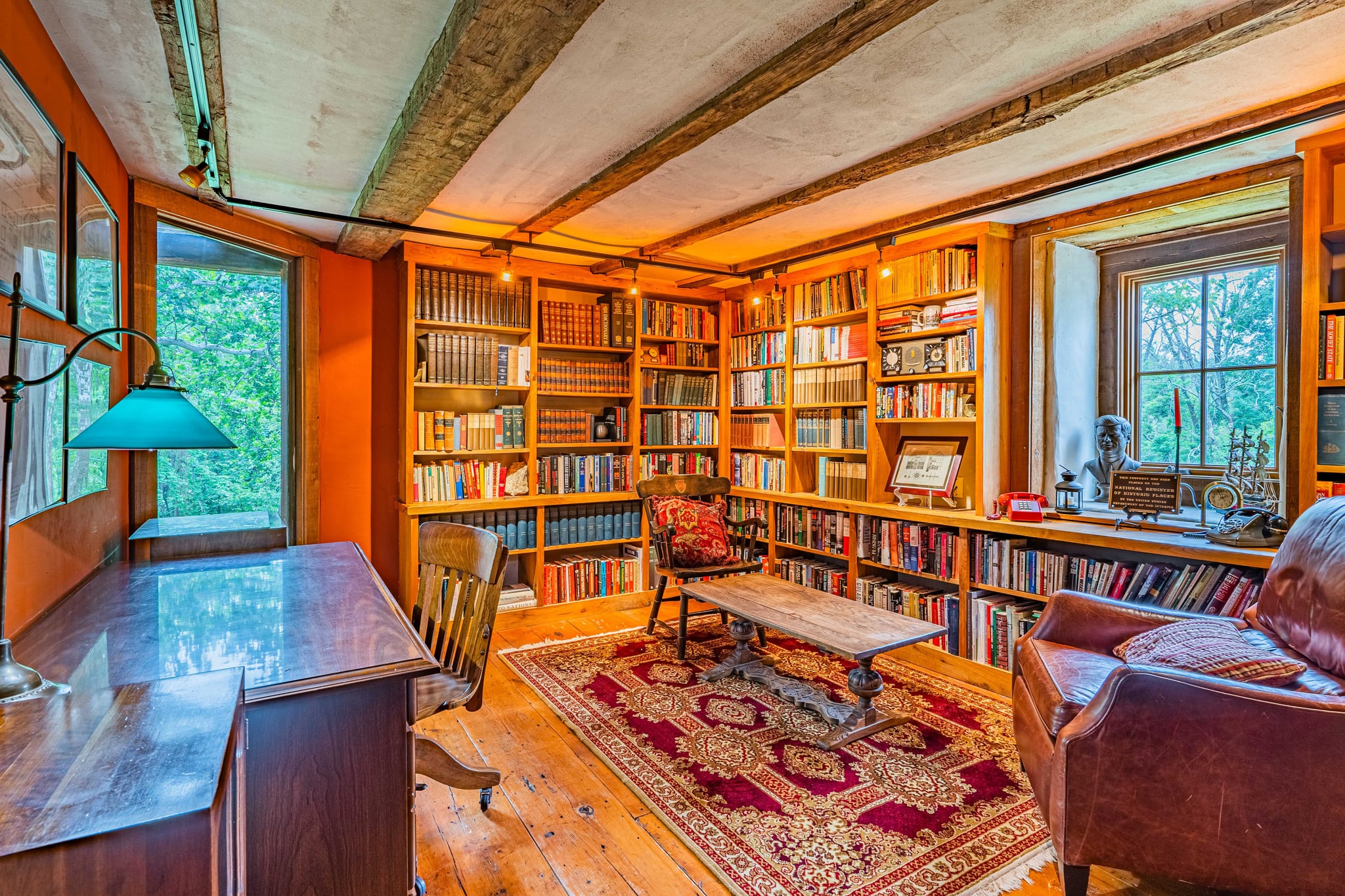 Library with floor-to-ceiling bookshelves, antique desk, and Persian rug
